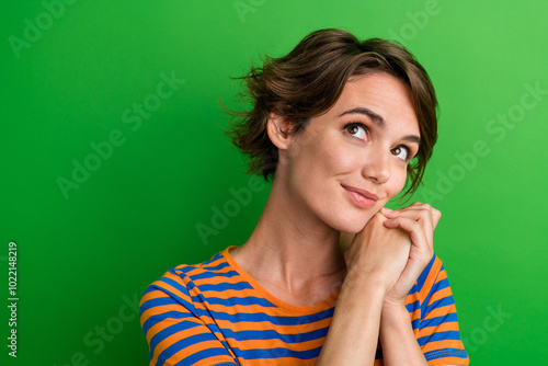 Photo portrait of pretty young girl look empty space hold hands together dressed stylish striped outfit isolated on green color background