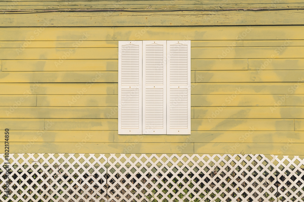 White shuttered window on a yellow painted house.