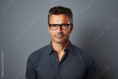 Portrait of a handsome middle-aged man wearing glasses against grey background