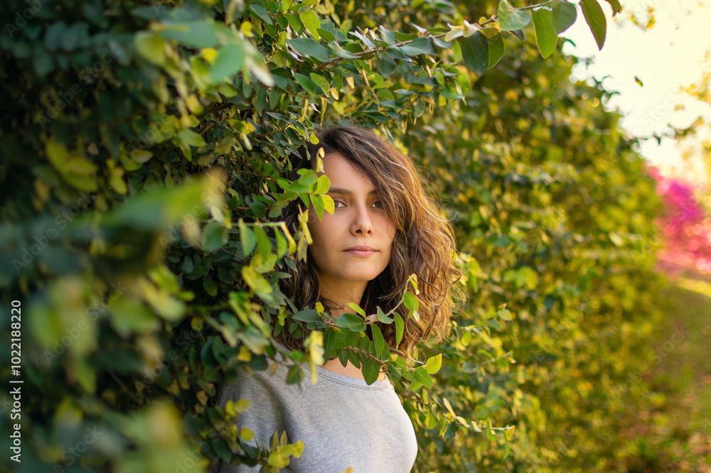 young woman smiling in the middle of a green wall full of plants and foliage young woman smiling in the middle of a green wall full of plants and foliage
