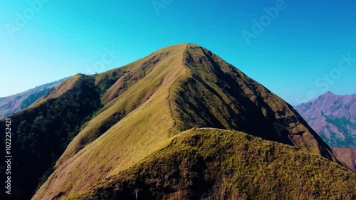 Experience breathtaking aerial views of the rolling hills in Sembalun, at the foot of Mount Rinjani, with expansive savanna turning golden at sunrise.