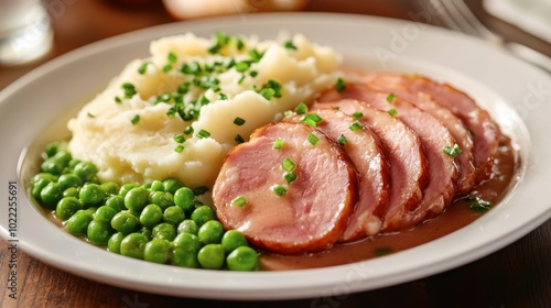 Sliced ham sausage served with creamy mashed potatoes and green peas for a classic comfort food meal.