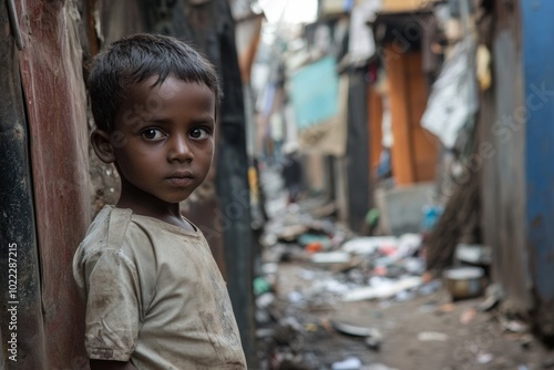 A young boy stands quietly in a narrow alley filled with debris, showcasing his resilience in a challenging urban environment photo