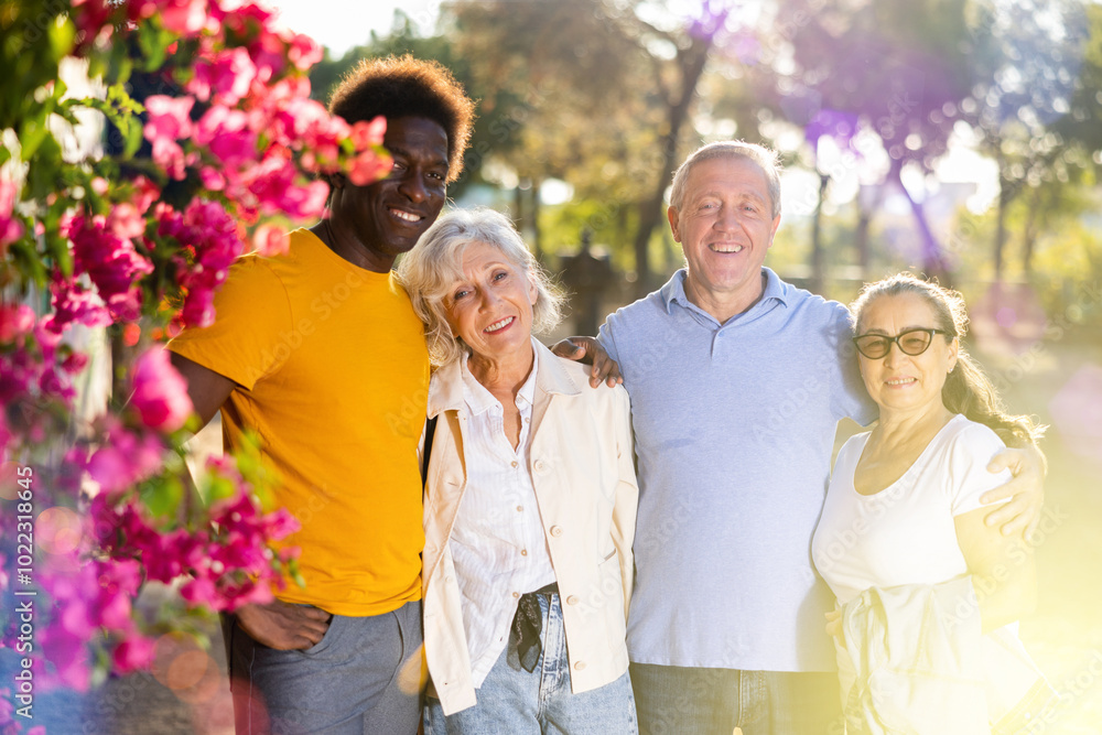 Naklejka premium Happy multiethnic people standing together, hugging and looking at the camera in the sunny weather, afternoon in autumn park