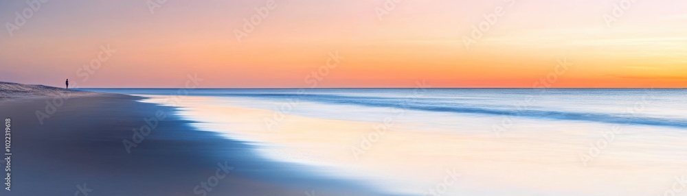 Obraz premium Stunning beach landscape at sunset, featuring calm waves and vibrant sky colors, perfect for relaxation and travel themes.