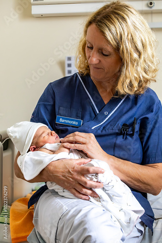 Stockholm, Sweden  A newborn baby girl being held by a hospital midwife. The nameplate says Barnmorska or Midwife in Swedish.