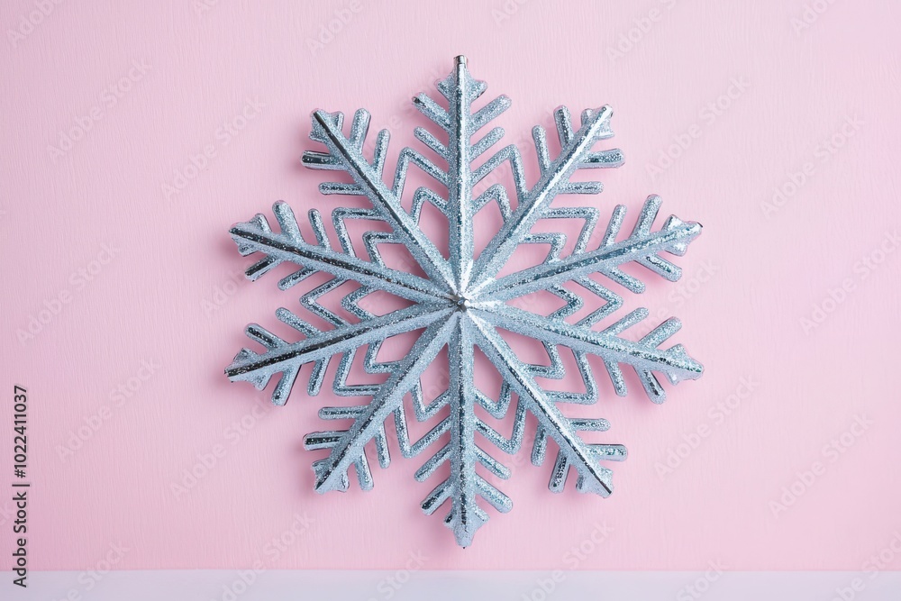 Metallic snowflake decoration on pastel pink background, perfect for winter themes and holiday celebrations. Metallic snowflake decoration on pastel pink background, perfect for winter themes and holiday celebrations.