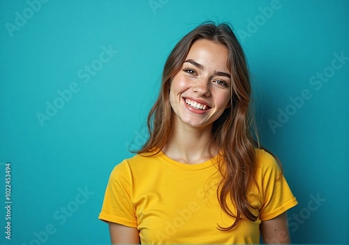 Relaxed Smiling Female Model in Yellow Shirt Posing Against a Blue Background - Capturing a Natural and Approachable Expression