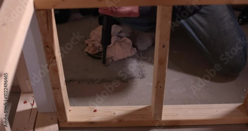 Construction worker using a powder actuated tool drives a fastener into a concrete floor with precision and skill. Selective focus