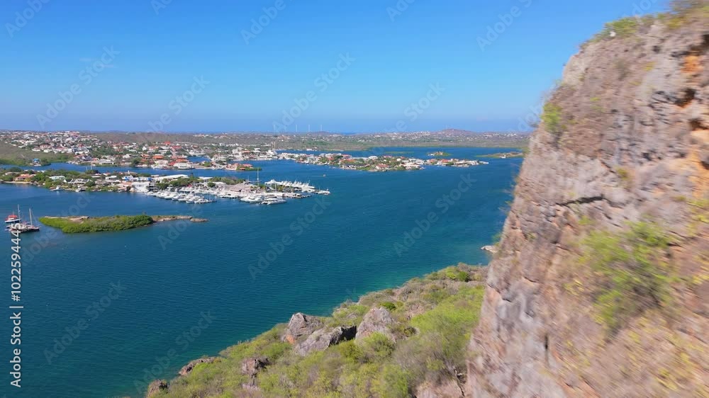 Aerial dolly of yachts anchored by a rugged coastline, clear waters and rocky cliffs below the horizon, views of Seru Kabritu Aerial dolly of yachts anchored by a rugged coastline, clear waters and rocky cliffs below the horizon, views of Seru Kabritu