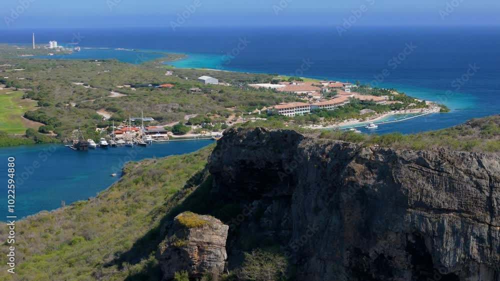 Aerial drone ascend of Seru Kabritu to reveal resort in the distance, capturing the scenic coastline and vibrant green landscape of Curacao Aerial drone ascend of Seru Kabritu to reveal resort in the distance, capturing the scenic coastline and vibrant green landscape of Curacao