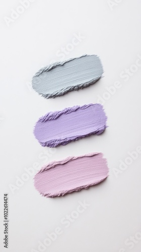 Three textured paint swatches in soft shades of gray and purple on a light background.