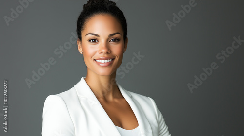 Confident businesswoman smiling in white blazer against dark gray background 