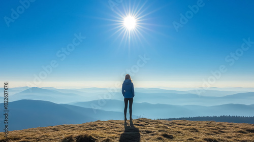 Woman stands on horizon hills with big shining sun above her head, Krkono�e, Czech Republic, minimalistic nature scene, blue beautiful skies. photo