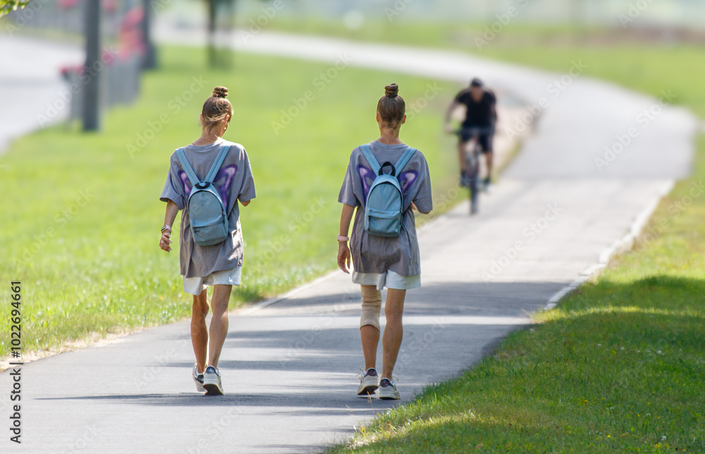 Two women walking on a path with backpacks Two women walking on a path with backpacks