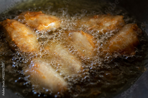 Chicken wings are fried in hot oil while frying in a pan