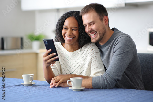 Happy couple in the kitchen checking smart phone