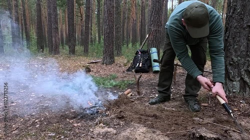 A man covers a fire in the forest with earth