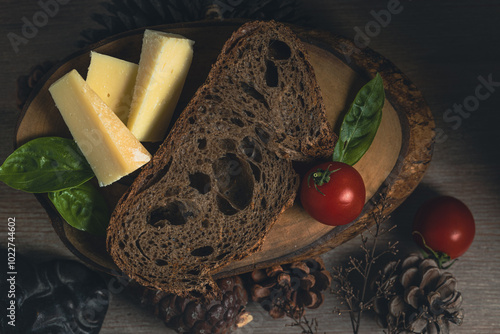 Dark and moody capture of a slice of buckwheat bread on wooden table with cones and dry tree branches emphasizing autumn season photo