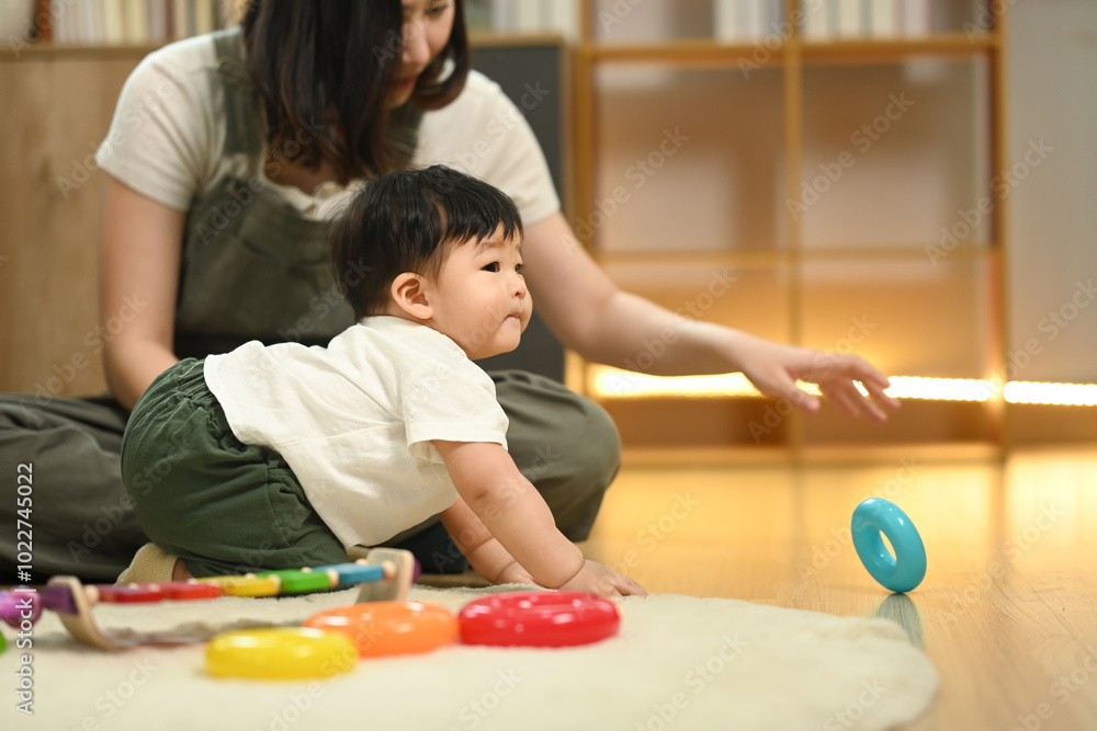 Fototapeta premium Loving young mother and cute toddler boy playing with educational didactic toy in living room