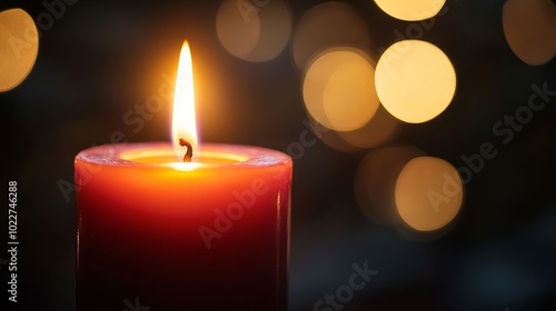 A single candle flame flickers brightly against a dark backdrop.