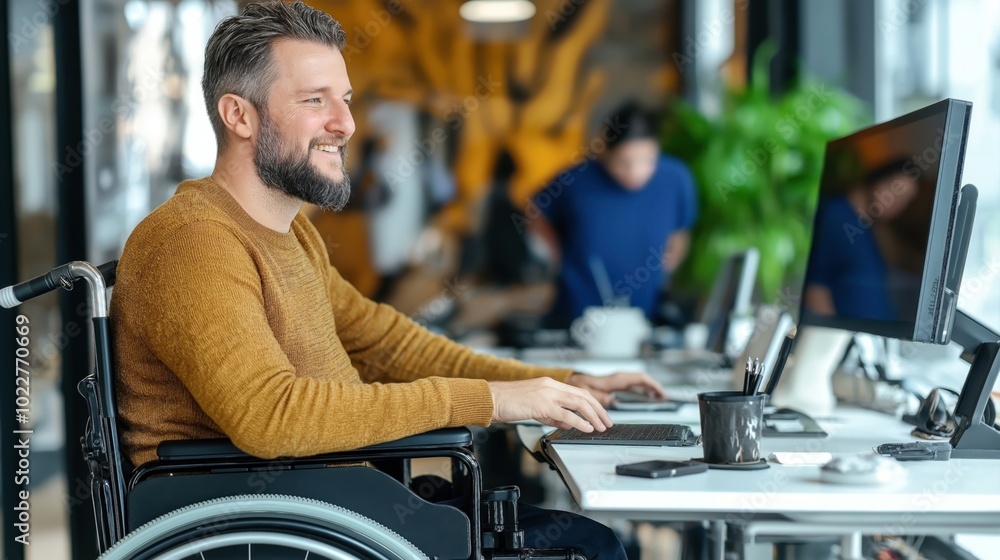 Man in wheelchair working at office desk using computer, smiling. Professional and inclusive work environment with modern technology and open workspace design. Man in wheelchair working at office desk using computer, smiling. Professional and inclusive work environment with modern technology and open workspace design.