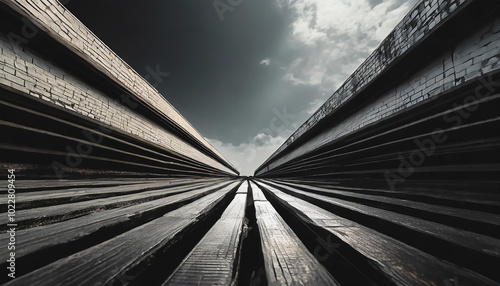 A unique perspective of wooden planks converging beneath a dramatic sky with contrasting light and shadows during daytime hours