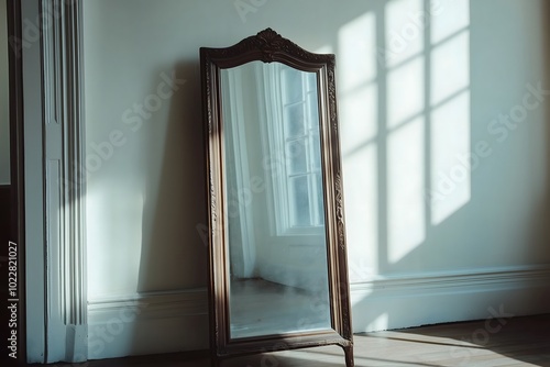 An antique mirror leaning against a white wall in an apartment