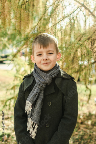 portrait of a school-age boy with blond hair in a coat in an autumn park. children's portrait