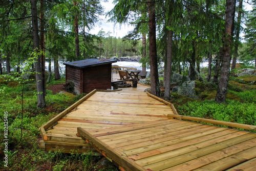 Wooden pathway leading to lakeside cabin in the woods
