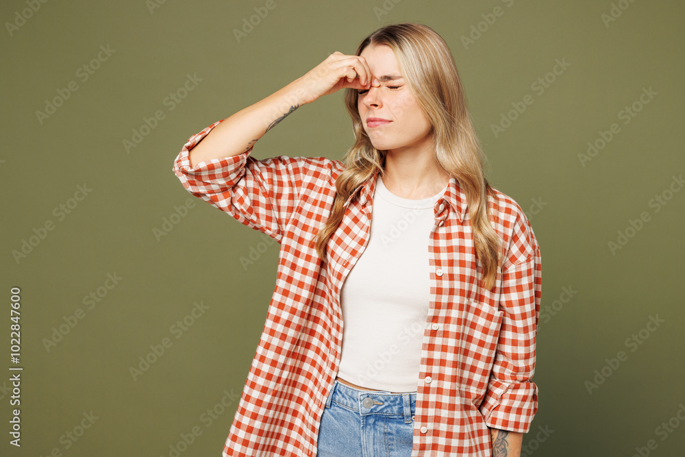 Young sad sick ill exhausted woman she wear red shirt white t-shirt casual clothes keep eyes closed rub put hand on nose isolated on plain pastel green background studio portrait. Lifestyle concept. Young sad sick ill exhausted woman she wear red shirt white t-shirt casual clothes keep eyes closed rub put hand on nose isolated on plain pastel green background studio portrait. Lifestyle concept.