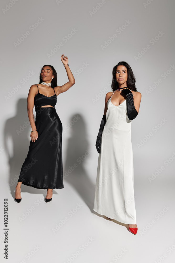 Two young women in chic outfits pose gracefully, exuding confidence and contemporary style. Two young women in chic outfits pose gracefully, exuding confidence and contemporary style.