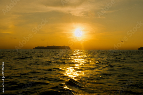 Breathtaking sunset over the ocean, with vibrant yellow hues painting the sky. Gentle waves reflect the warm colors, creating a serene and picturesque scene that captures nature's beauty at dusk
