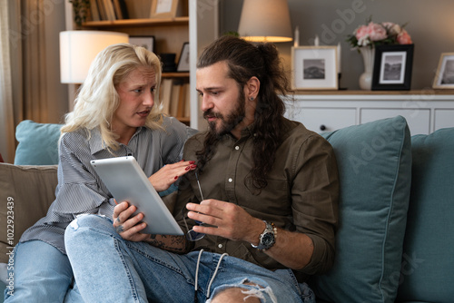 Woman comforts her husband who was confirmed via received email on tablet that he got fired at work and that he is no longer employed in the company where he expected to be promoted. Job lost concept