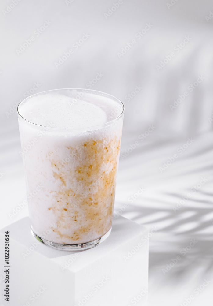 Cold brew coffee with milk and palm leaf shadow on white background Cold brew coffee with milk and palm leaf shadow on white background