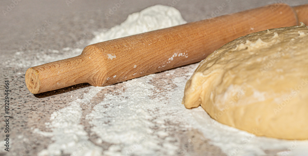 Fresh raw dough and rolling. Raw dough for pizza or bread baking. Dough for pizza and rolling-pin on table. Preparation homemade pizza on kitchen table Fresh raw dough and rolling. Raw dough for pizza or bread baking. Dough for pizza and rolling-pin on table. Preparation homemade pizza on kitchen table