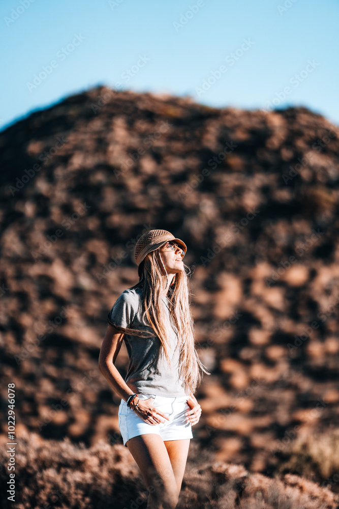 Young woman enjoying a sunny day outdoors against a rocky mountain background Young woman enjoying a sunny day outdoors against a rocky mountain background