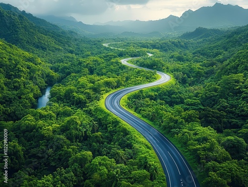 a drone's eye view captures a winding highway meandering through a lush forest, highlighting the beauty of nature and the thrill of adventure on a sustainable journey