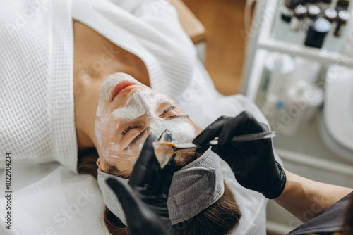 Close up of cosmetologist make face mask for woman client in saloon.Dermatology,beauty concept.