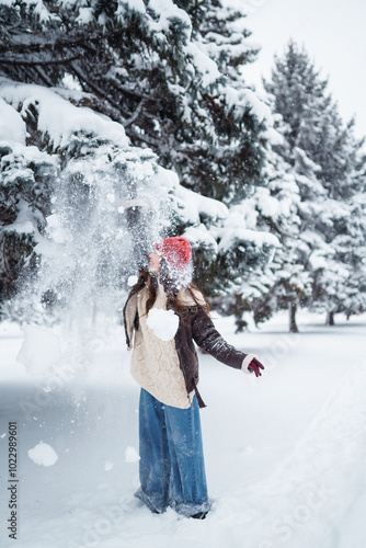 Young woman having fun with snow on a winter day in the park.  Concept of fun, relaxation, winter holidays.