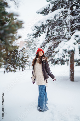 Young woman having fun with snow on a winter day in the park. Concept of fun, relaxation, winter holidays.