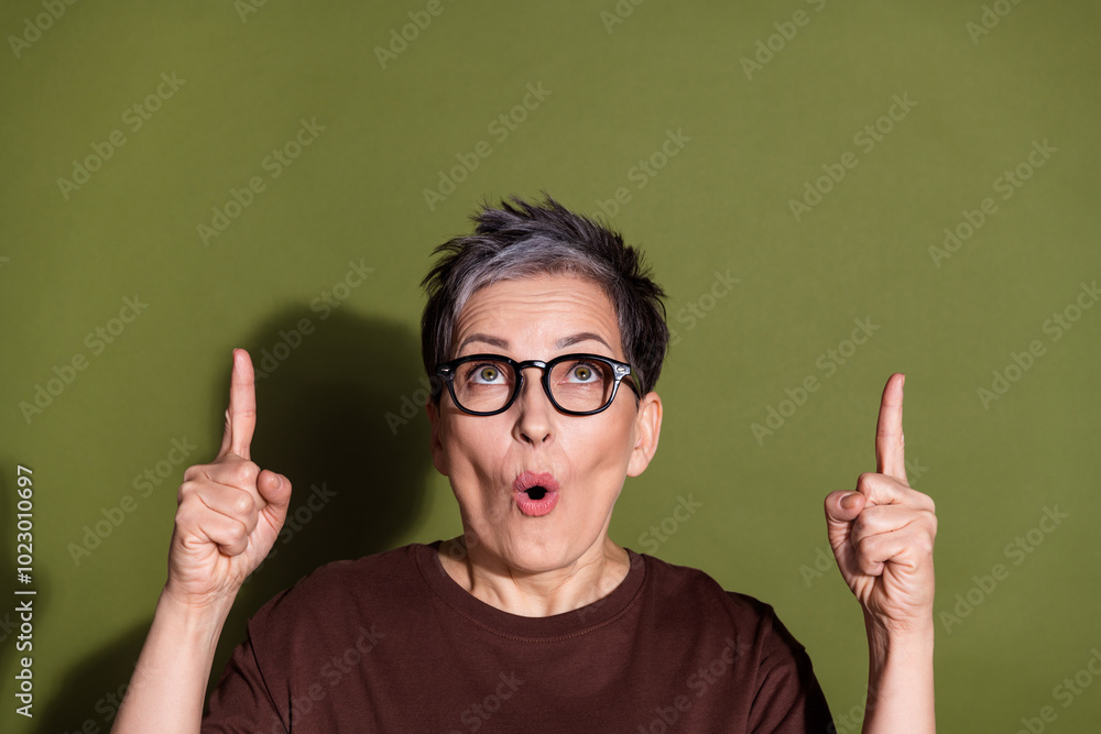 Photo portrait of pretty senior female point up amazed look empty space wear trendy brown outfit isolated on khaki color background Photo portrait of pretty senior female point up amazed look empty space wear trendy brown outfit isolated on khaki color background