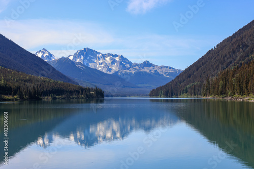 mountains are reflected in the smooth surface of duffey lake, british columbia