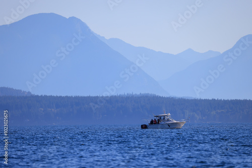a fishing boat off the coast of Vancouver Island with many layers of mountains at the horizon