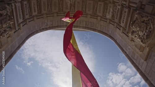 The Romanian flag waving in the wind at the triumphal arch. The Red, Yellow and Blue tricolor. The wind that flutters and moves the flag hanging from the monument of the triumphal arch in Bucharest. photo