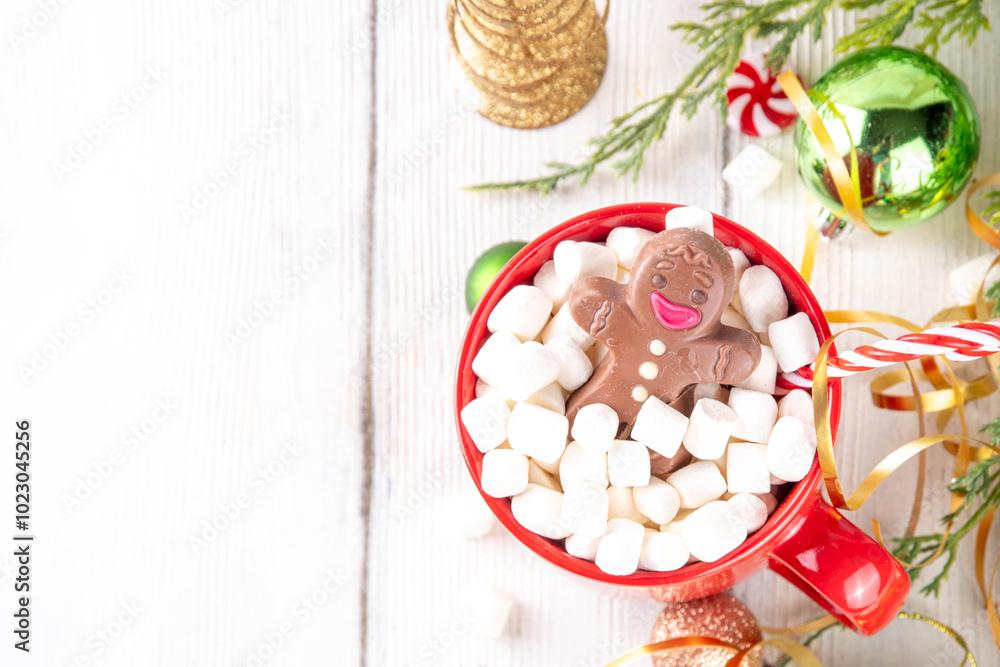 Naklejka premium Funny Christmas hot chocolate with marshmallow and chocolate gingerbread man taking chocolate bath in red mug, on festive holiday decorated background