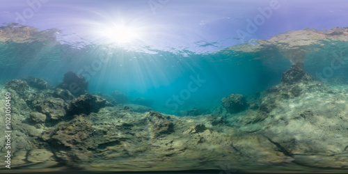 Foto A serene underwater scene with sunbeams penetrating the surface, lighting up the rocky ocean floor in a 360-degree view