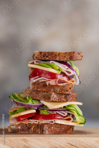 Big healthy sandwich for breakfast, with ham, cheese, homemade curry sauce, tomato, cucumber, avocado and onion, served on a table, close up image with a copy space. Tasty sandwich for breakfast. 