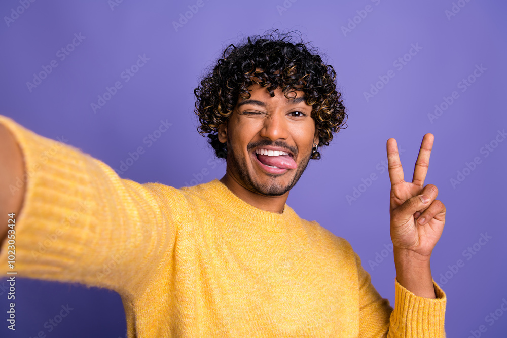 Photo of positive cheerful blogger man wear stylish clothes make video v-sign isolated on violet color background Photo of positive cheerful blogger man wear stylish clothes make video v-sign isolated on violet color background