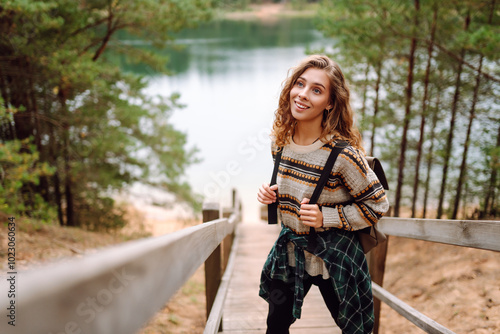 Young tourist woman enjoys the view of the mountain lake. Solitude with nature. Active lifestyle.